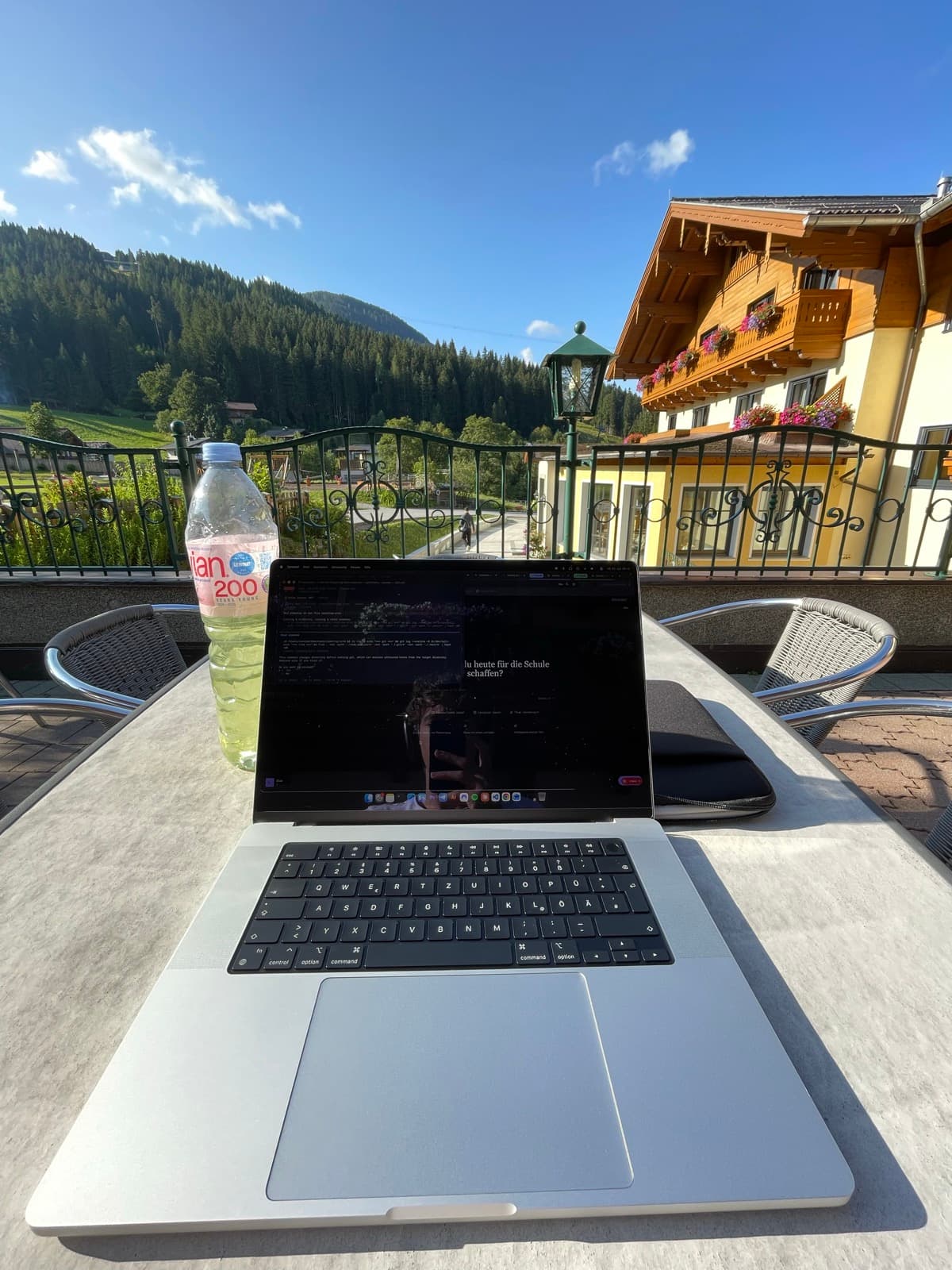 Laptop mit geöffnetem Scooly auf einer Terrasse in den Bergen
